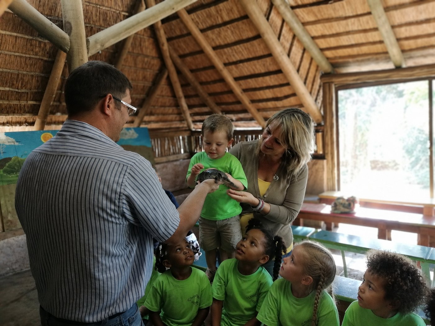 Holding a baby crocodile, with teacher's hands close by just in case