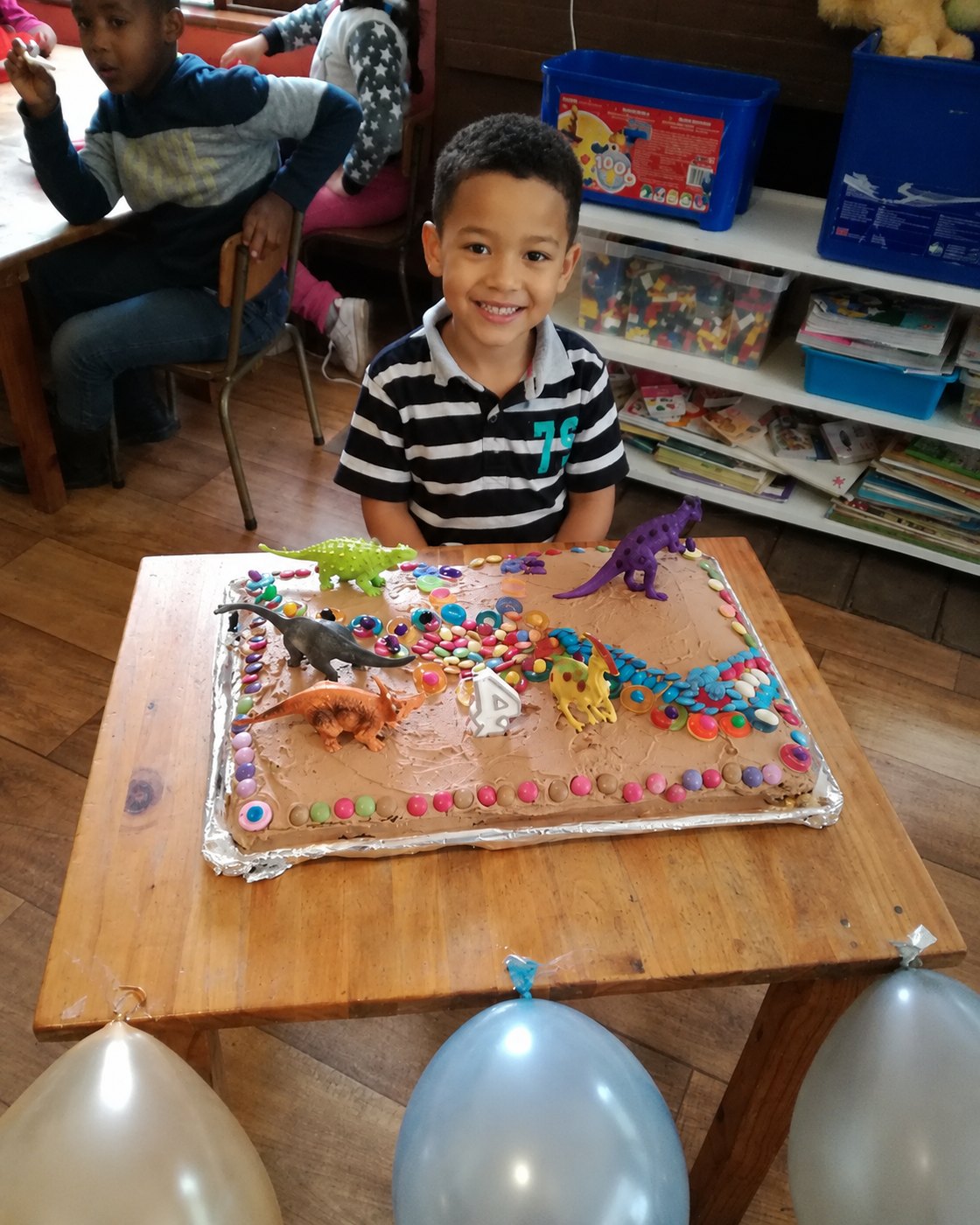 A very proud birthday boy with his dinosaur cake